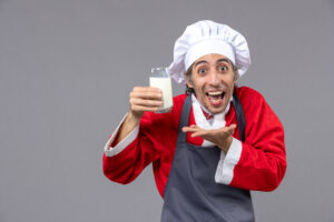 Young man with classic milk mustache, smiling while holding a glass